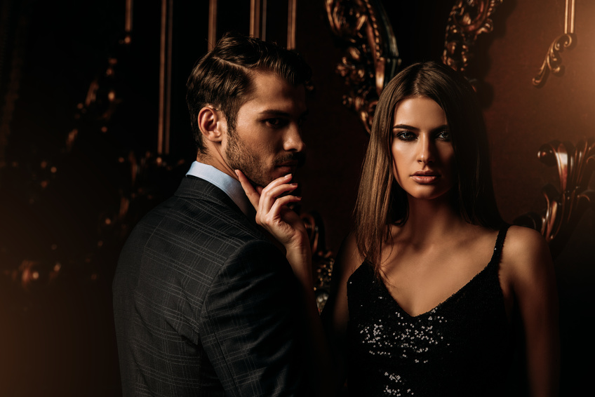 coppia in abito elegante una coppia si incontra per un incontro occasionale elegante e lei, in un abito di pallettes nere, accarezza il viso di lui, in giacca e camicia